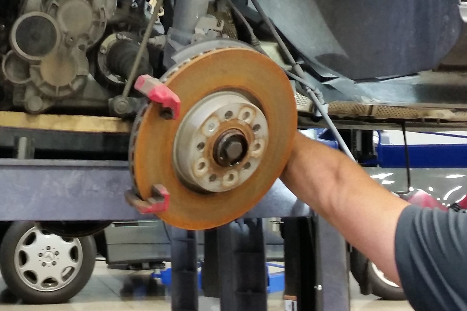 Technician removing a worn brake rotor, with the wheel hub and ABS ring exposed