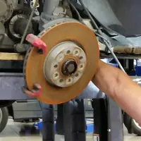 Technician removing a worn brake rotor, with the wheel hub and ABS ring exposed