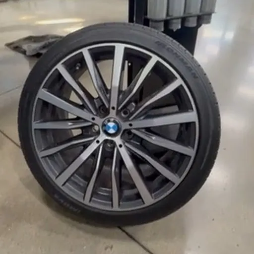 Tire and alloy wheel on the shop floor — uneven tread wear is the most common sign of a bad alignment